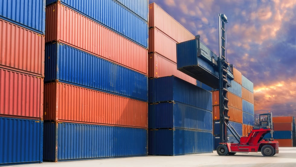 Forklift raising a shipping container in a ship yard