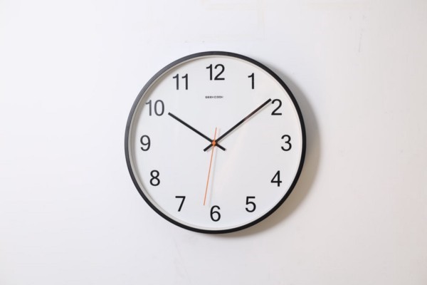 A standard face clock on a white wall