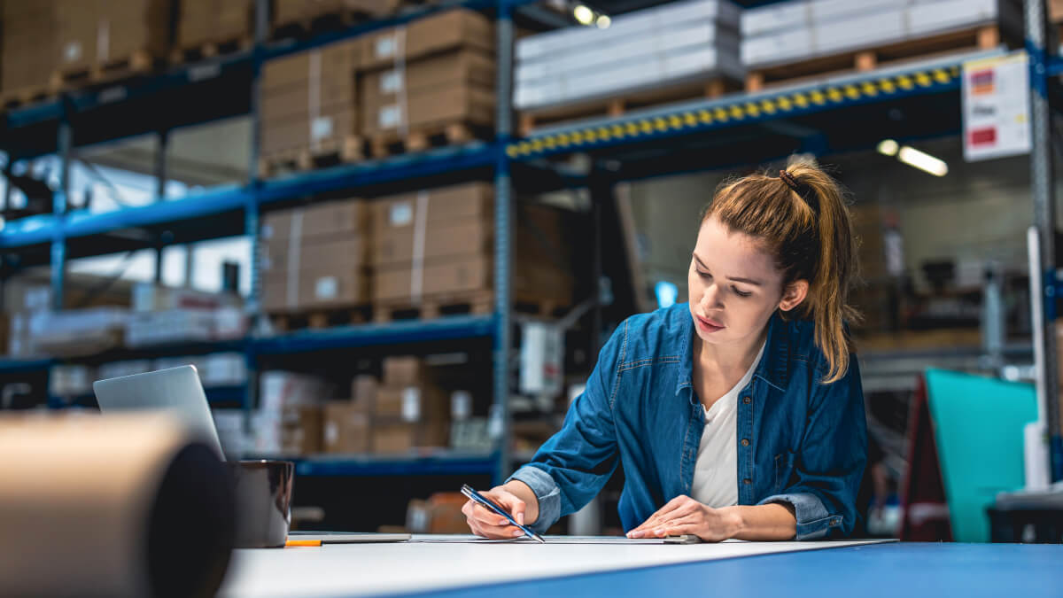 Femme dessinant des plans à son bureau dans un entrepôt