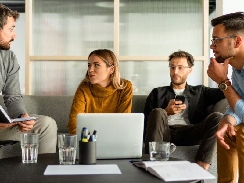 Group of four colleagues talking around a table in the office